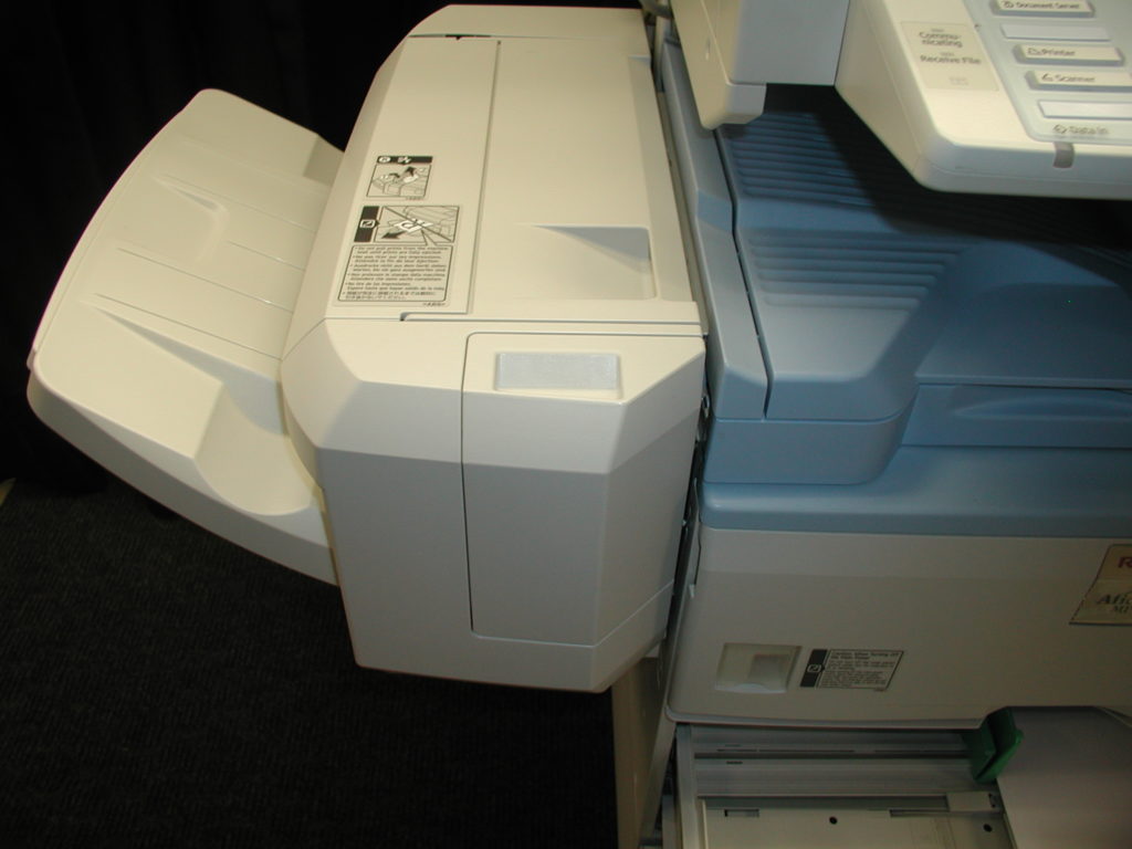 A printer is sitting on the floor next to some papers.